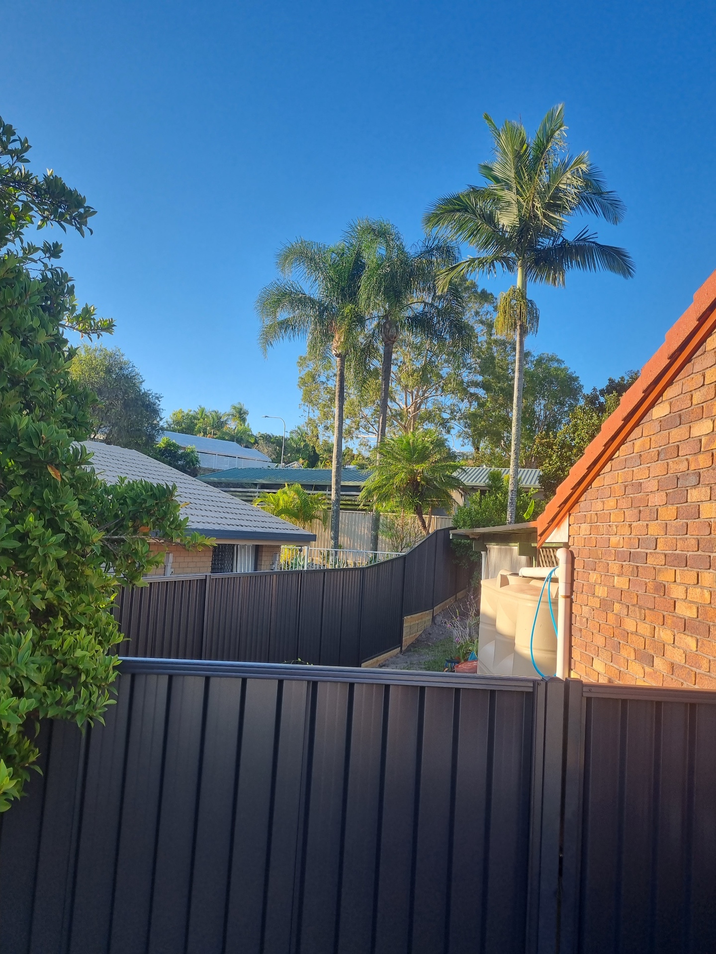 Dark grey Colorbond boundary fence stepping with the slope of the block.