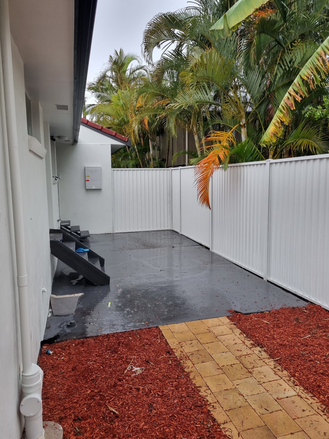 Wide cream Colorbond fence run wrapping the side of a home with concrete path access.